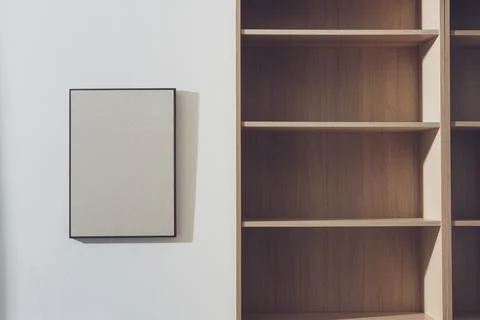 Empty bookcase and blank picture hanging on the wall Stock Photos