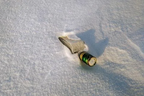 An empty bottle of alcohol is lying in the snow Stock Photos