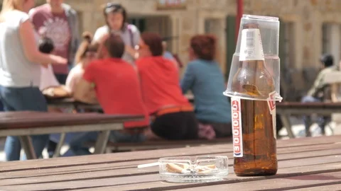 Empty Bottle of Beer and Smoked Cigarettes in an Ashtray on a wooden Table Stock Footage 89733819