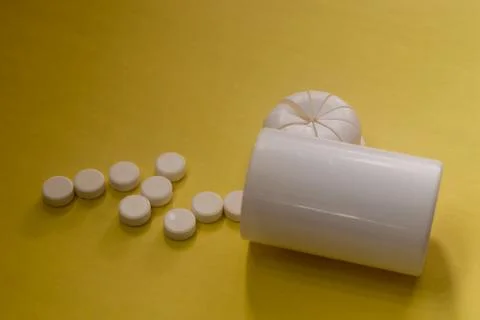 Empty bottle of pills, white tablets on a yellow background Stock Photos