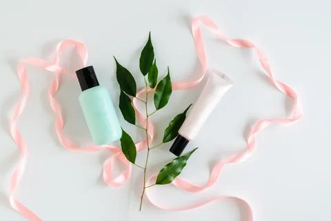 Empty bottles for cosmetics on white background with pink satin ribbon and gr Stock Photos