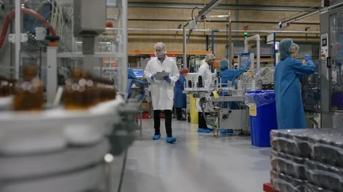 Empty bottles moving on conveyor belt and worker operating control board Stock Footage 107982906