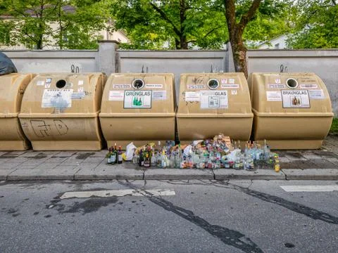 Empty bottles standing in front of overfilled containers in a city. A symbol of Stock Photos
