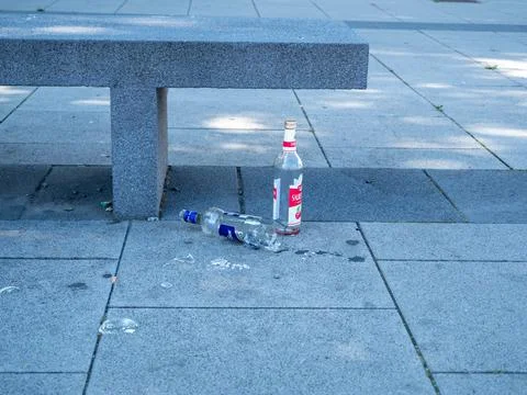 Empty bottles thrown at the bench. Garbage near the stone bench. Stock Photos