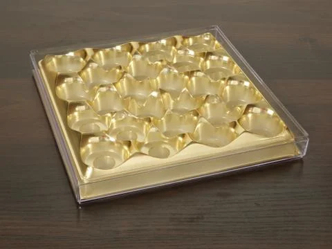 Empty box from sweets of gold colour on a wooden table. Stock Photos