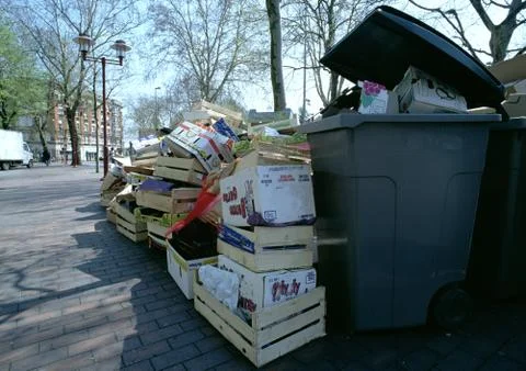 Empty boxes and crates piled up beside overflowing trash bin Foto stock