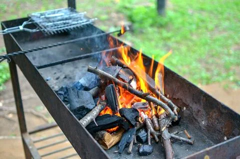 An empty brazier with a burning bonfire fire against the background of green Фото