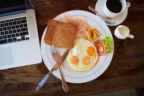 Empty, breakfast and coffee on table in home with laptop for nutrition, protein Stock-Fotos