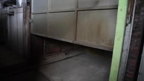 Empty brick lined tunnel kiln entrance stands open behind a rusted steel door Vídeo Stock 346737857
