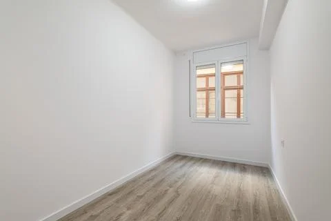An empty bright room with a window in which the windows of a nearby house are Photos