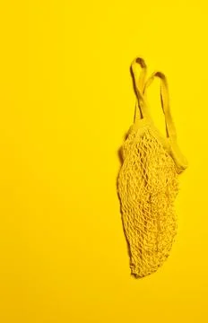 Empty bright yellow mesh bag on yellow paper Stock Photos