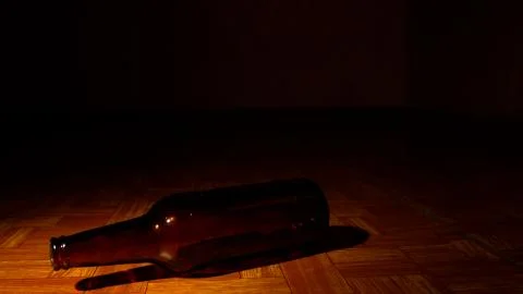 Empty brown bottle on a floor in a dark room Stock Photos