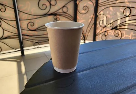 An empty brown paper coffee cup is on the table Stock Photos