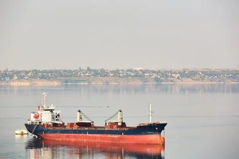 Empty bulk carrier cargo ship with deck cranes sailing on a river calm water Stock-Fotos