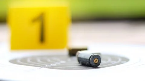 Empty bullet casing on a shooting target, with a blurred black number 1 in .. Stock Photos