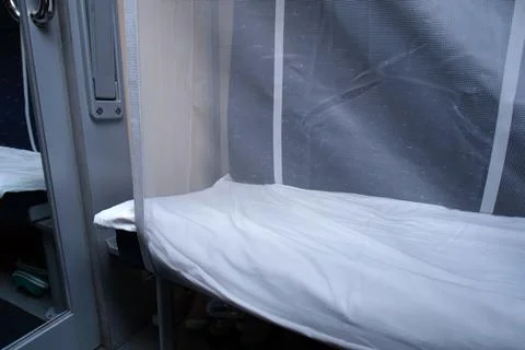 Empty bunk with white sheet and safety guard inside train cabin. Passenger .. Stock Photos
