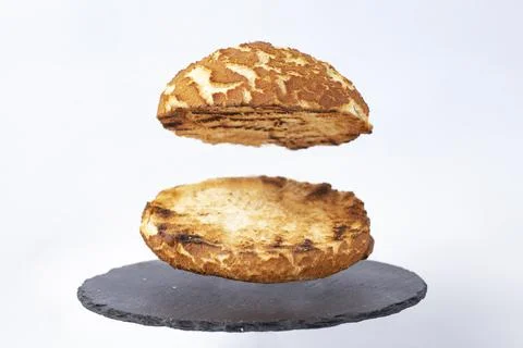 Empty burger bun, levitating over a black stone tile, Stock Photos