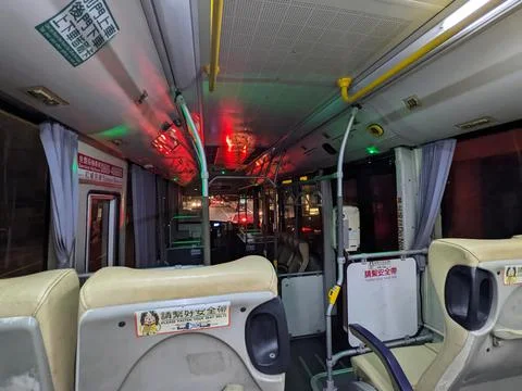 An empty bus interior viewed from the back of the bus with a driver in the front Stock Photos
