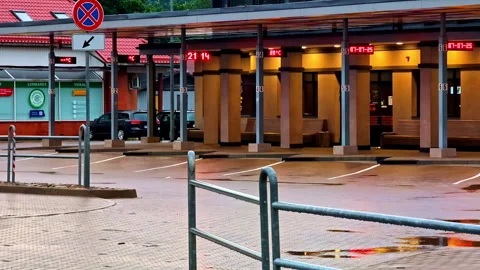 Empty bus station platform after rain with wet pavement and digital time Stock Footage 320873731