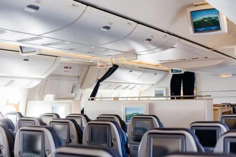 Empty cabin of a large aircraft with rows of seats Stock Photos