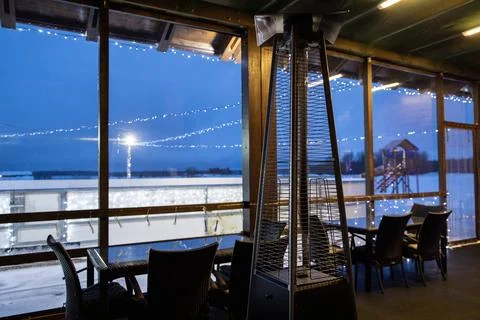 Empty cafe seating area by a large window with a view of a brightly lit outdoor Stock Photos