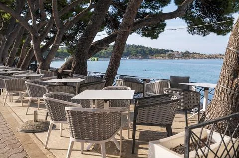 Empty cafe table and modern woven chairs set on an outdoor seaside promenade Stock Photos