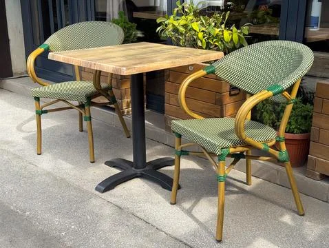 Empty cafe table with two woven bistro chairs on a sunny sidewalk terrace. .. Foto stock