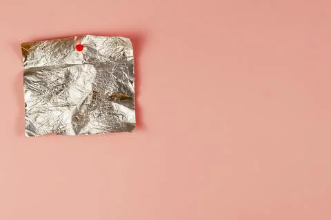 Empty candy wrapper pinned to pink background. Rectangular piece of crumpled  Foto stock