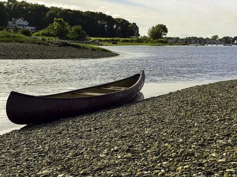 Empty canoe sits at the edge of river Stock Photos