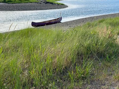 Empty canoe sitting on the water's edge Stock Photos