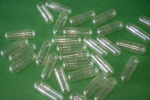 Empty Capsule Pill on a Bright Green Background Stock Photos