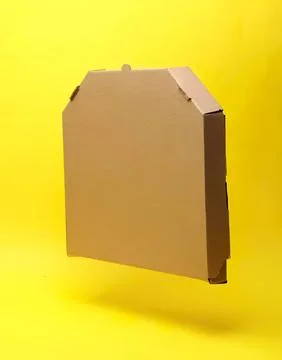 Empty cardboard box floating against yellow background Stock Photos