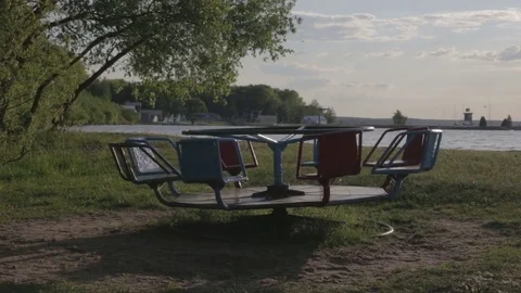 An empty carousel spins against the backdrop of a lake Vidéo 82312531