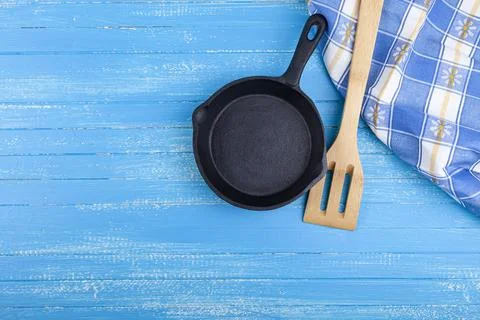 Empty cast iron pan on a blue wooden background. Stock Photos