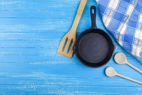 Empty cast iron pan on a blue wooden background. Stock Photos