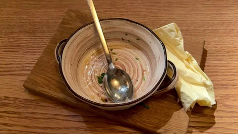 Empty Ceramic Bowl With Spoon, Creamy Broth Traces And Crumpled Napkin On Wooden Stock Footage 325231627