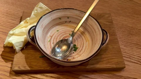 Empty Ceramic Bowl With Spoon, Creamy Broth Traces And Crumpled Napkin On Wooden Stock Footage 325232218