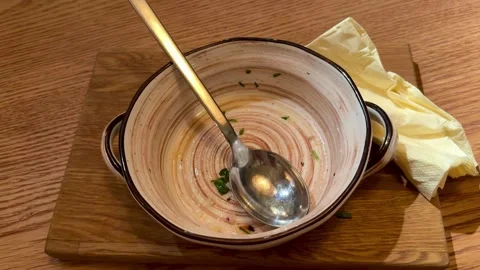 Empty Ceramic Bowl With Spoon, Creamy Broth Traces And Crumpled Napkin On Wooden Stock Footage 325232661