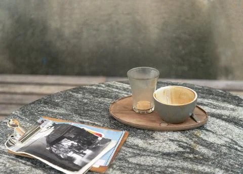 An empty ceramic coffee cup and water glass rest on a minimalist wooden tra.. Stock Photos