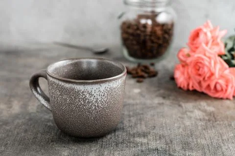 An empty ceramic coffee cup, a jar of coffee beans and a bouquet of roses o.. Stock Photos