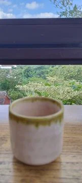 Empty ceramic cup on wooden table in coffee shop with natural background. Stock Photos
