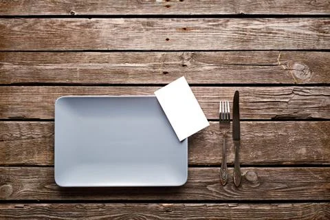 Empty ceramic dish with fork, knife and blank menu Fotos de archivo