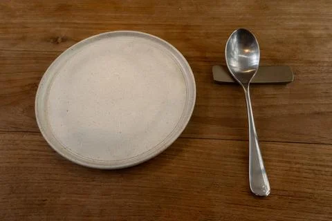 Empty Ceramic Plate and Spoon on Rustic Wooden Restaurant Table Foto stock