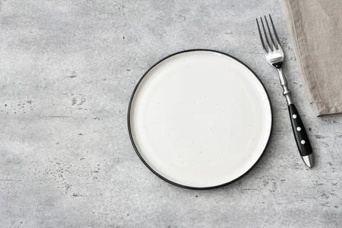 Empty ceramic plate with fork on gray stone table, minimal rustic table setting Stock Photos