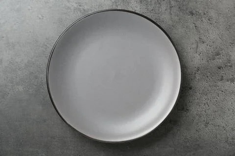 Empty ceramic plate on grey table, top view Stock Photos