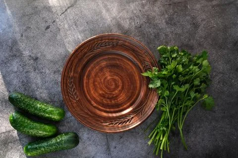 Empty ceramic plate, next to cucumbers and herbs. Diet concept. Stock Photos