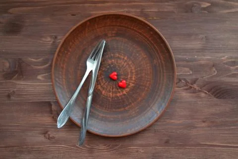 Empty ceramic plate with small red hearts on a dark wooden table Stock Photos