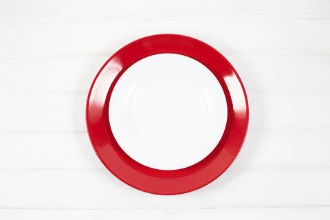 Empty ceramic red and white plates on white wood background. Stock Photos