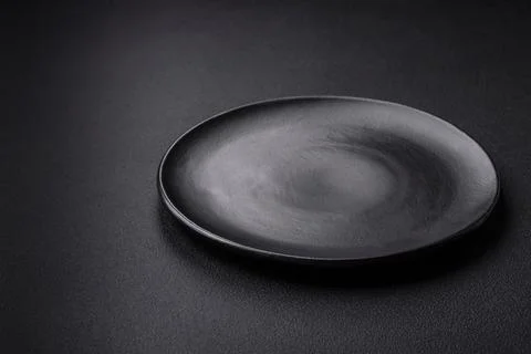 Empty ceramic round plate on dark textured concrete background Stock Photos