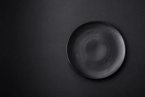 Empty ceramic round plate on dark textured concrete background Stock Photos